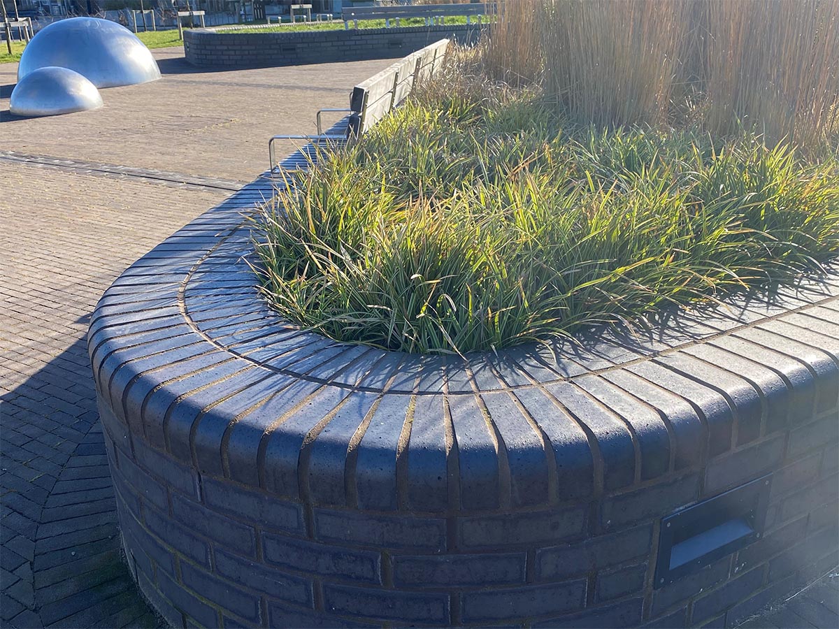 tapered staffs blue bricks at Wichelstowe Canalside sit flush with bullnose timber benches in the new square